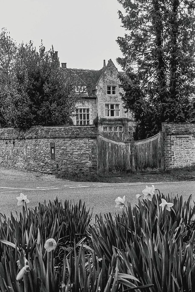 Historic house, stone wall and wooden gate photographed in black and white at Great Milton