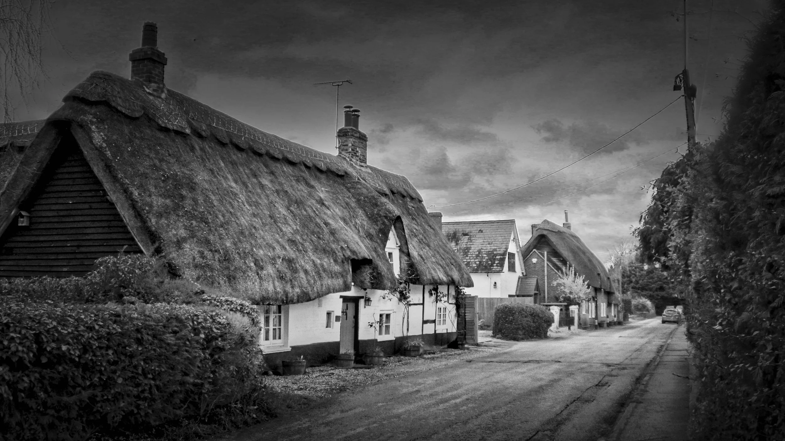 Traditional thatched cottages along a village lane photographed in black and white