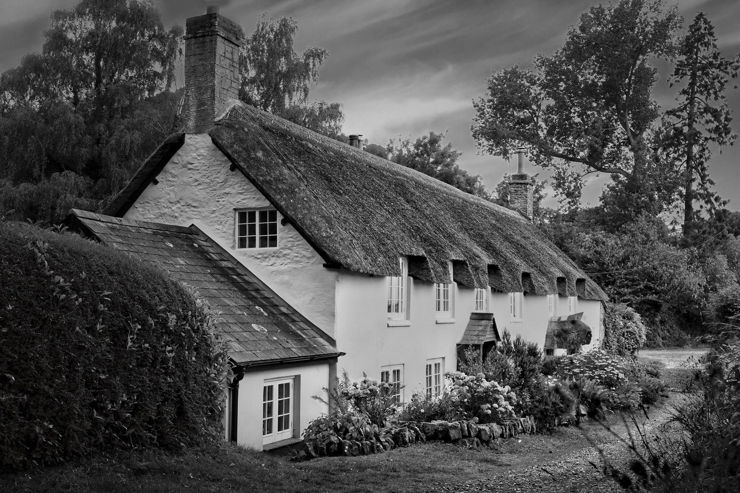 Traditional thatched cottage in a rural setting photographed in black and white