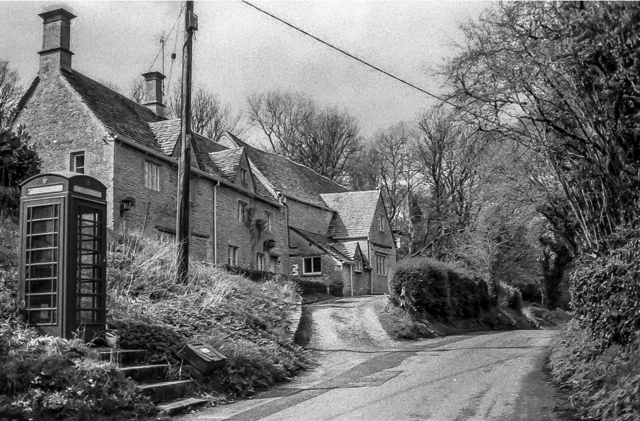 Chedworth village street with traditional stone cottages and telephone box