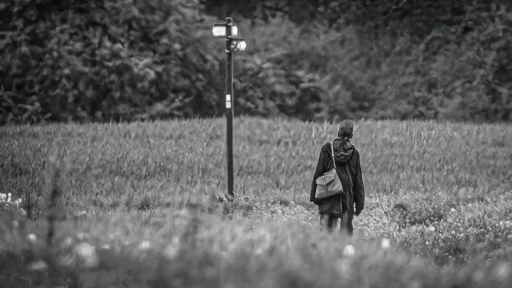 Woman standing in a field near a footpath sign
