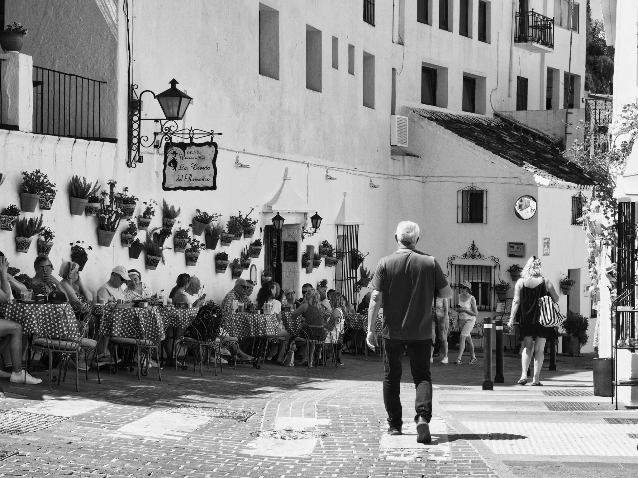Man walking past a wall of plant pots in Mijas, Andalusia
