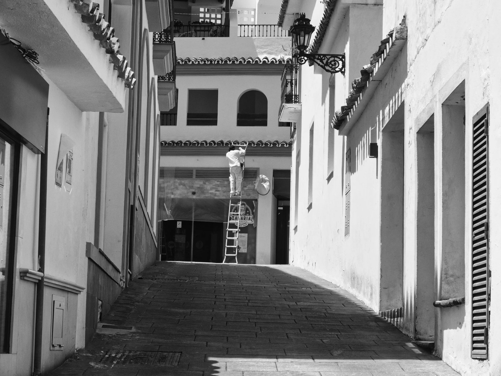 Man on ladder symmetrical alley whitewashed buildings andalusia