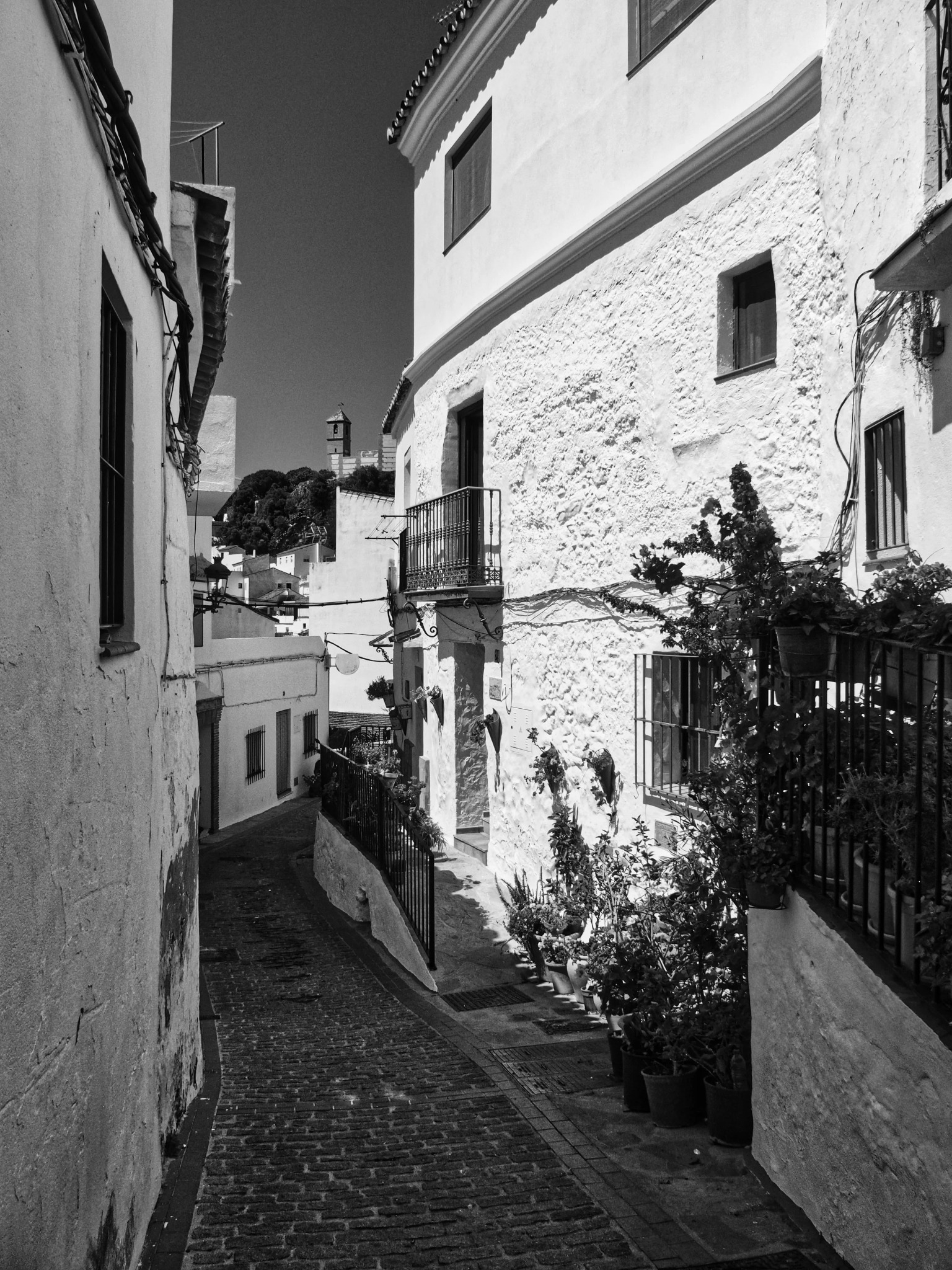 White village alley balcony plants church tower andalusia
