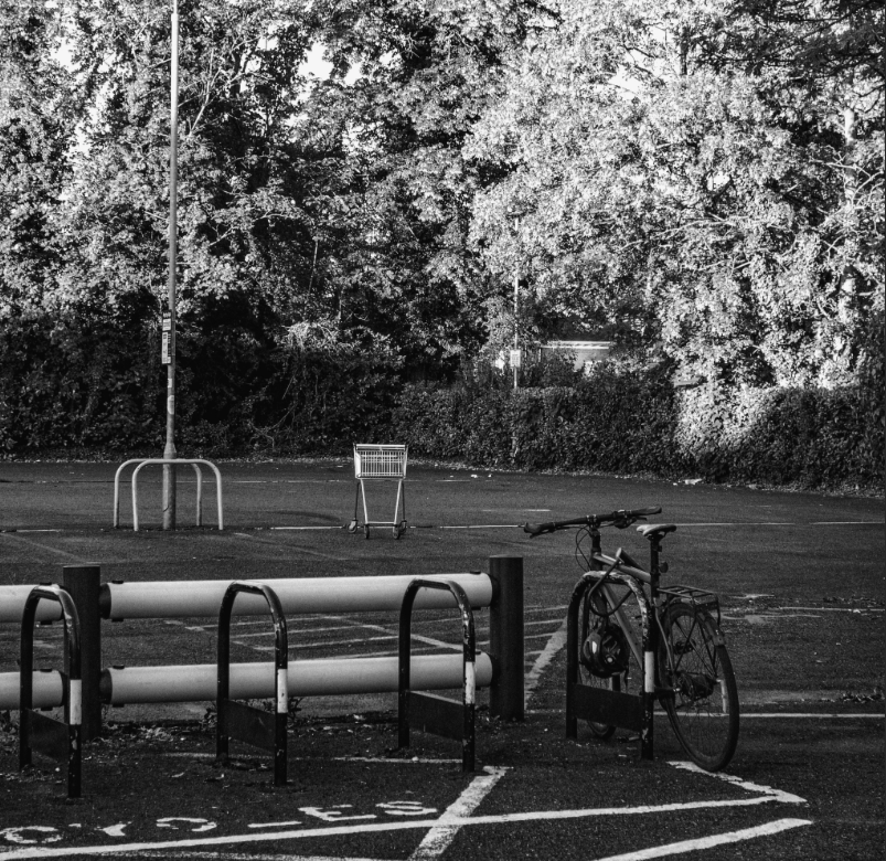 Bicycle and abandoned shopping trolley in a car park